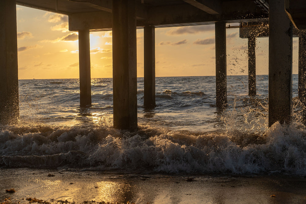 Waves breaking beneath a pier at sunrise
