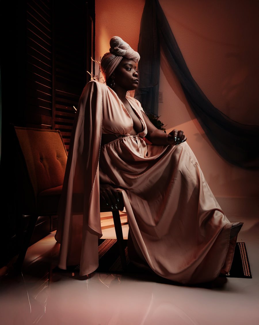 Portrait of a woman in a blush gown and headwrap in a warm, shuttered room