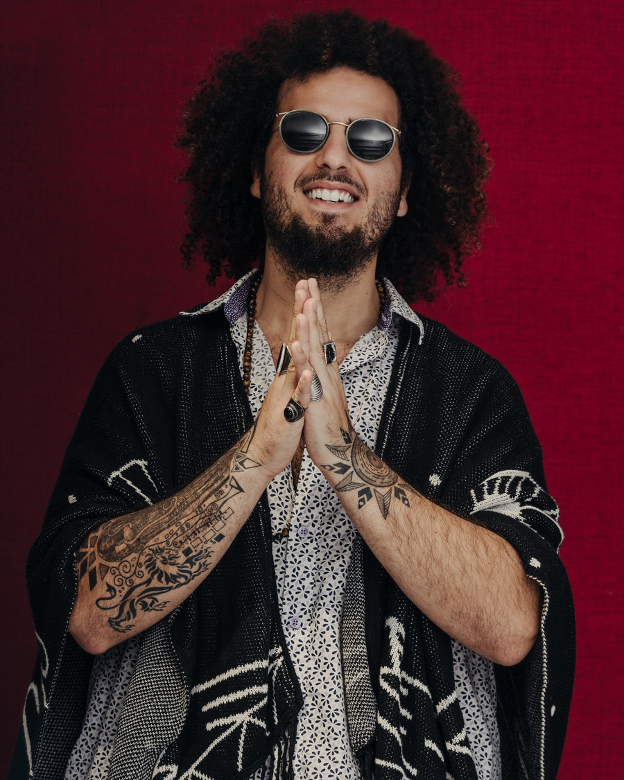 Portrait of a man in an embroidered jacket and sunglasses against red