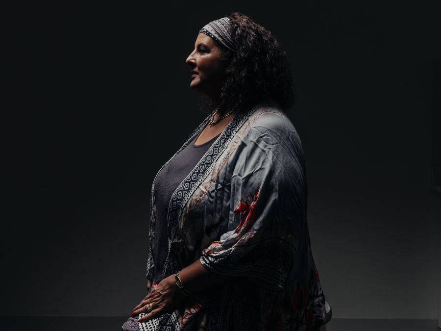 Studio portrait in profile of a woman in a patterned kimono and headwrap