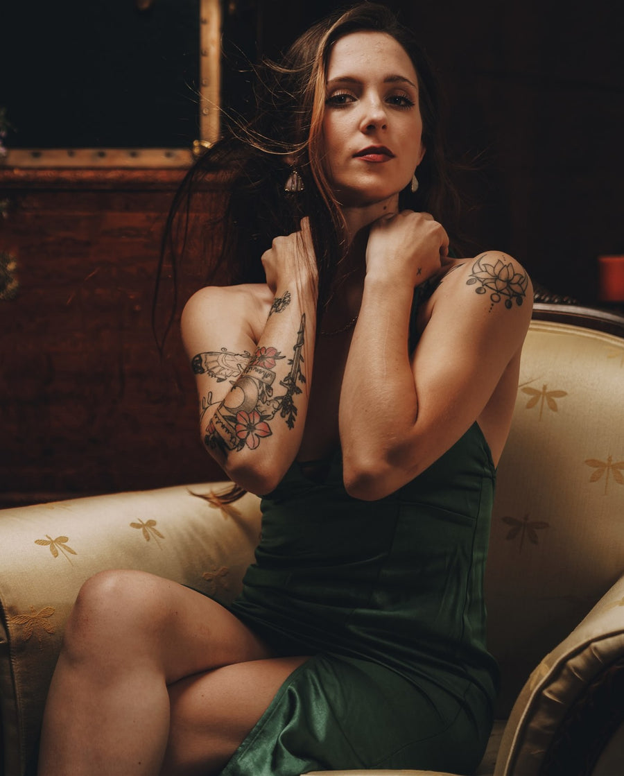 Portrait of a woman in a green satin dress reclining on a sofa